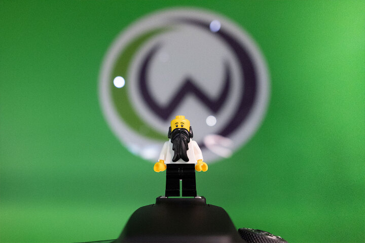 A LEGO mini-figure is standing in front of DCW logo